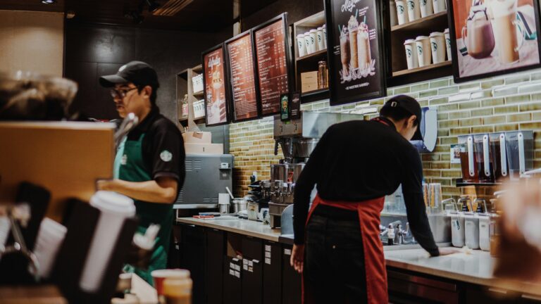 Two worker's perform tasks at a Starbucks. SHARE and investors flag concerns about the company's labour relations.